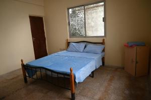 a bedroom with a bed with a blue comforter and a window at Stylish Hilltop King Bed Apartment with Free Parking and Wifi in Wuţayyah