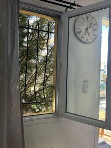 a clock on a wall next to a window at Chez Sabrina, à Nanterre Paris La Défense, maison individuelle qui donne sur jardin in Nanterre