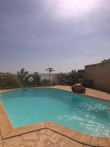 una piscina con acqua blu di fronte a una recinzione di Chambre Vue sur Mer a Saint-Leu