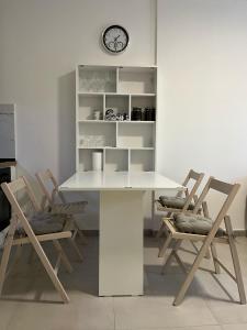 a white table with chairs and a clock on a wall at Sunshine Apt Qerret-Golem Beach in Golem