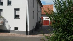 a white house with a red door and a staircase at Ferienwohnung Wassergasse in Kapellen-Drusweiler +15 photos