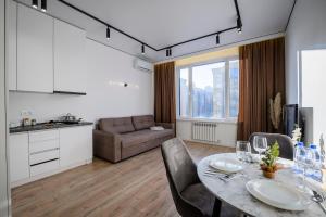 uma cozinha e sala de estar com mesa e cadeiras em Пять НОВЫХ апартаментов БИЗНЕС КЛАССА в ЖК R-HOUSE в 100 м от MEGA em Almaty