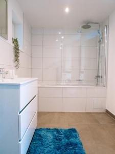 uma casa de banho com uma banheira, um chuveiro e um tapete azul em La Suite Cosy em Roppenheim