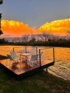 a wooden deck with a table and chairs on the water at Cabañas Rio Soñado in Valle Grande