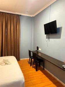 a hotel room with a desk and a television on the wall at The Grand Hotel 2 in Bandar Indah