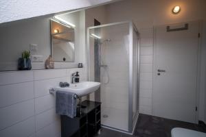 a white bathroom with a sink and a shower at JS-Apartment in Balingen
