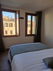 a bedroom with a large bed with two windows at SAN LORENZO APARTMENTS 5054 in Venice