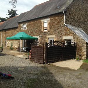 a brick building with two gates and a green umbrella at Gîte Aristide Mont Saint Michel in Sacey