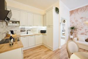 une cuisine avec des armoires blanches et un salon dans l'établissement OKRA Apartment Pescara Centro, à Pescara