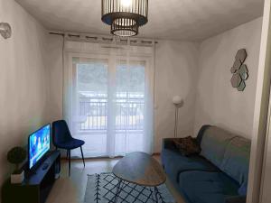 ein Wohnzimmer mit einer blauen Couch und einem Fernseher in der Unterkunft Appartement T2 - PMR à 750 Mètres de la Station Thermale d'Avène (34) in Avène