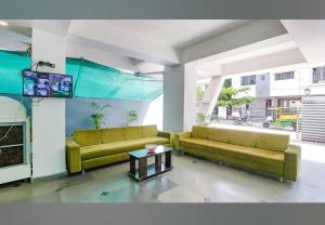 a living room with two couches and a tv at Hotel Ocsa Inn in Nagpur