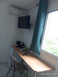 einen Schreibtisch mit einem Monitor und einem Stuhl neben einem Fenster in der Unterkunft Chambre Vue sur Mer in Saint-Leu