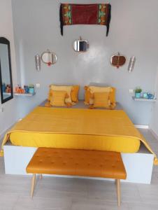 a bedroom with a large bed with yellow sheets and a bench at Villa diam la paix in Guediawaye