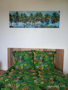 een bed met een groene sprei met palmbomen bij Chambre Vue sur Mer in Saint-Leu