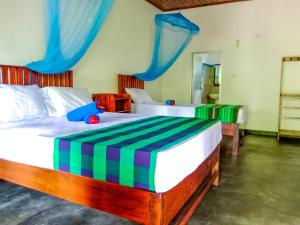 two beds in a bedroom with blue and green curtains at Pride Rock Villa in Sigiriya