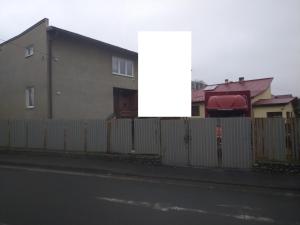 a fence in front of a house with a building at Penzión Bardejov pri Nemocnici in Bardejov