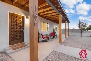 a porch with red chairs and a wooden door at ValleyVibe: Modern Comfort in North Valley - an Irvie Home in Albuquerque