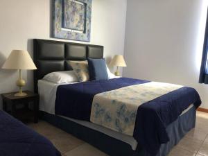 a bedroom with a large bed with a blue comforter at Hotel Formigas na Figueira in Tibagi