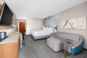 a hotel room with a bed and a couch at Courtyard by Marriott Fort Lauderdale North/Cypress Creek in Fort Lauderdale