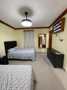 a bedroom with two beds and a flat screen tv at ApartaHotel El Bonao in Higuey