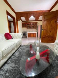 ApartaHotel El Bonao في Higuey: غرفة معيشة مع أريكة بيضاء وطاولة زجاجية