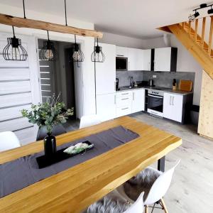 a kitchen with a wooden table and white cabinets at Apartmány Louka in Vaclavov u Bruntalu