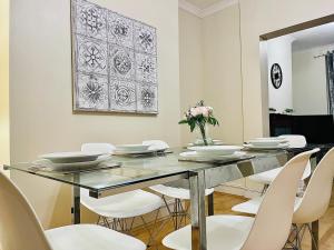 a dining room with a glass table and white chairs at 2 Bedroom Flat In Central London in London