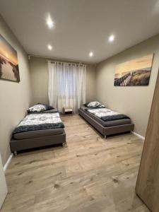 Habitación con suelo de madera y 2 camas. en Soho Ferienwohnung, en Rodenbach