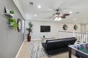 a living room with a black leather couch and a tv at 5BR 3BA Home - King Beds - Fast Wifi home in Victorville
