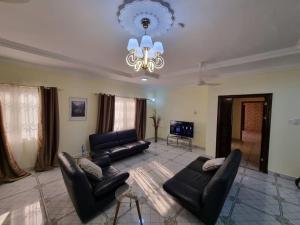 uma sala de estar com mobiliário de couro preto e um lustre em B's Classic and Cozy Apartments em Cape Coast