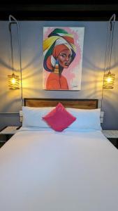 a bedroom with a bed with a painting on the wall at Maloka Boutique Hostel in Cartagena de Indias