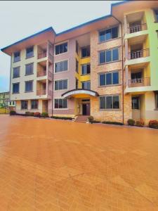 un gran edificio de apartamentos con un aparcamiento de ladrillo en Kate Villa, en Kumasi