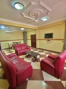 a living room with red couches and a tv at Kate Villa in Kumasi