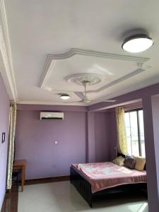 een slaapkamer met paarse muren en een plafond bij Kate Villa in Kumasi