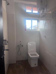 a white bathroom with a toilet and a window at BKR homestay 2bhk in Itānagar +9 photos