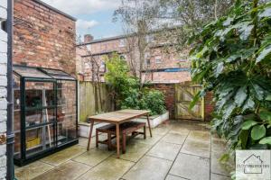 a patio with a wooden table and a greenhouse at Elegant Home from Home in Manchester