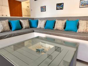ein Sofa mit blauen Kissen und einem Glastisch in der Unterkunft South Coast Private on the Beach in Christchurch