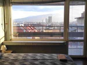 Schlafzimmer mit einem großen Fenster mit Stadtblick in der Unterkunft Panorama Rooms in Sofia