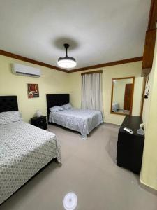 una camera d'albergo con due letti e uno specchio di ApartaHotel El Bonao a Higuey
