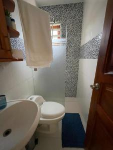 ein Badezimmer mit einem weißen WC und einem Waschbecken in der Unterkunft ApartaHotel El Bonao in Higuey