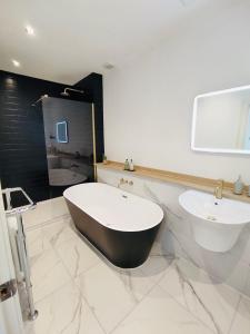 uma casa de banho com uma banheira em preto e branco e um lavatório. em Glenarch House em Dalkeith