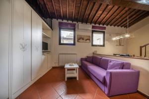 sala de estar con sofá púrpura y mesa en Verdi - Ampio Monolocale in Santa Croce, en Florencia