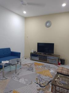 a living room with a blue couch and a flat screen tv at KASIH JERAI HOMESTAY, Gurun, Guar Chempedak in Guar Chempedak