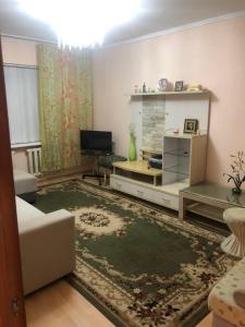 ein Wohnzimmer mit einem Sofa und einem TV in der Unterkunft Квартира in Almaty