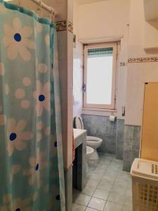 y baño con aseo y cortina de ducha. en Lavinio 100 mt dalla spiaggia, en Anzio