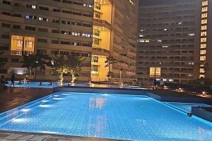 a large swimming pool in a city at night at Private condo w/ balcony near Batasan, Ateneo, UP, Diliman, The Residences at Commonwealth in Manila