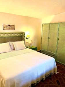 a bedroom with a large white bed and green cabinets at LA DEPENDANCE in Su Forti