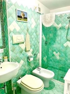a green tiled bathroom with a toilet and a sink at LA DEPENDANCE in Su Forti