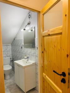 uma casa de banho com um lavatório branco e um WC. em Agroturystyka Dom Wśród Sosen em Rzędkowice