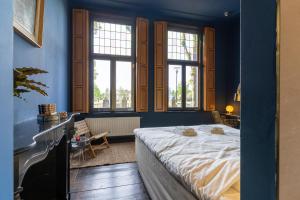 1 dormitorio con paredes azules, 1 cama y ventanas en Boutique hotel Lytel Blue, en Riethoven